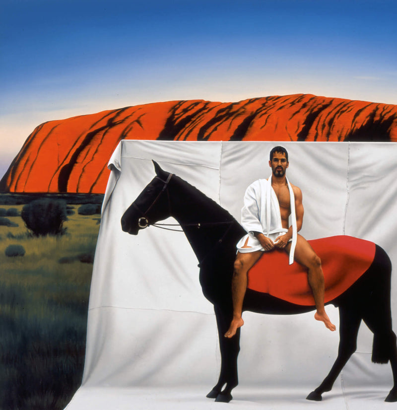 Man wearing martial arts uniform sitting on horse in front of Uluru